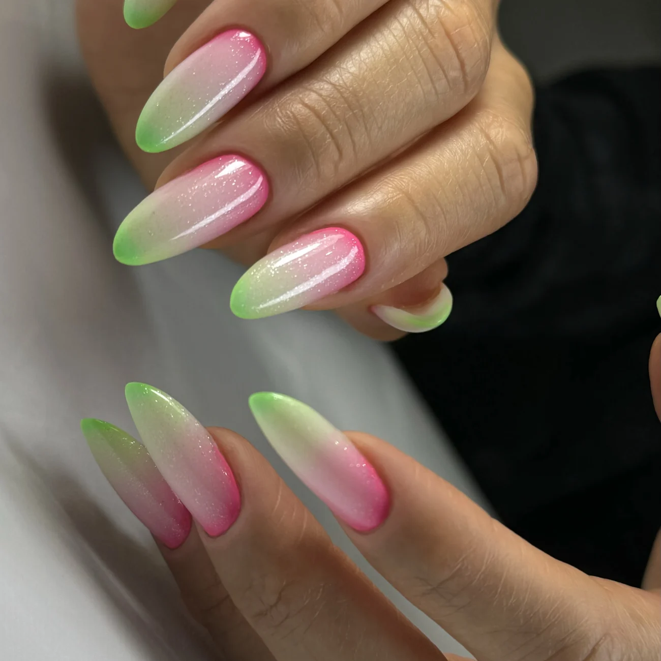 Almond-shaped nails with neon green and pink ombre design.