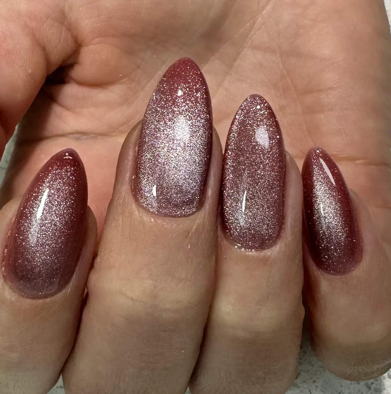 Almond-shaped nails with a shimmering brown finish.