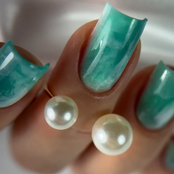 Turquoise nails with pearl accents and a glossy finish.