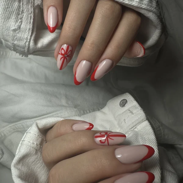 White almond-shaped nails with red accents and artistic designs.